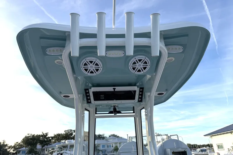 Slide: The Image of 2023 Tidewater 2410 Bay Max boat with T-top, rod holders, and speakers under a clear sky. - 54