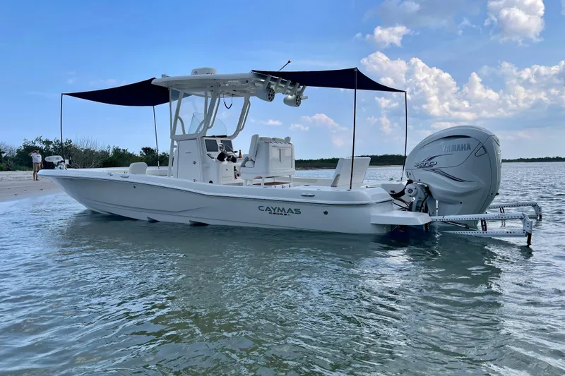 Slide: The Image of 2020 Caymas 28 HB boat with Yamaha engine, anchored near a sandy shore under a blue sky. - 2