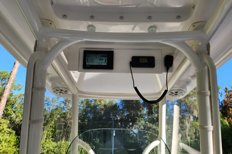 Slide: The Image of 2020 Caymas 28 HB boat console with electronics and speakers, surrounded by trees. - 30