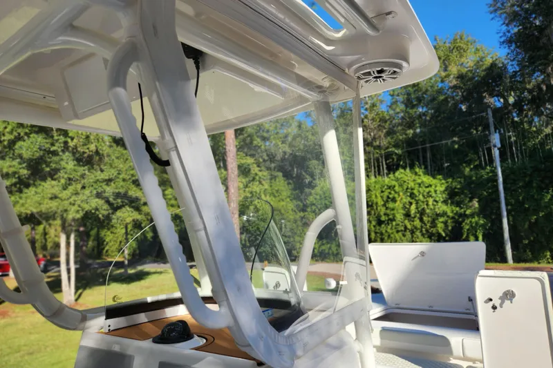 Slide: The Image of 2020 Caymas 28 HB boat interior with canopy and seating, surrounded by lush greenery. - 37