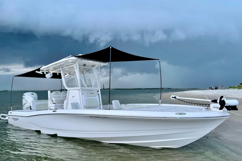 Slide: The Image of 2020 Caymas 28 HB boat anchored on a sandy beach under a cloudy sky. - 4