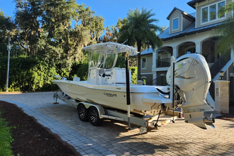 Slide: The Image of 2020 Caymas 28 HB boat on trailer in driveway, surrounded by lush greenery. - 8
