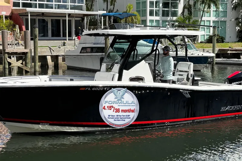 The Image of 2022 Blackfin 272 CC boat docked, featuring promotional signage on the side. - 0