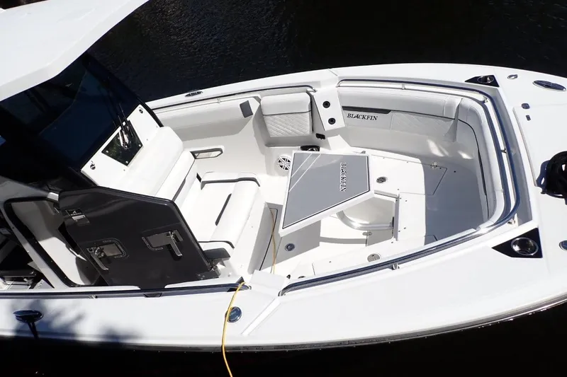 Slide: The Image of 2022 Blackfin 272 CC boat interior with seating and table, docked by the water. - 10