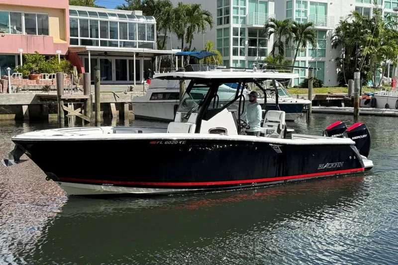 Slide: The Image of 2022 Blackfin 272 CC boat cruising in a marina with waterfront homes. - 2