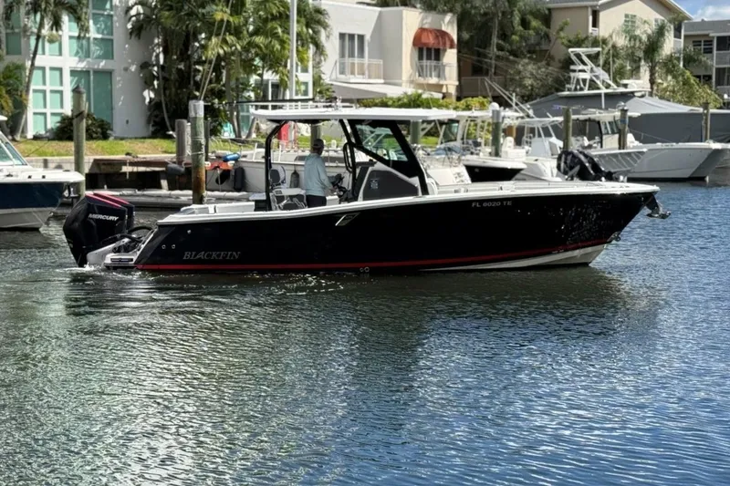 Slide: The Image of 2022 Blackfin 272 CC boat cruising in a marina with waterfront buildings. - 3