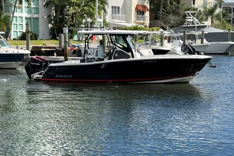 Slide: The Image of 2022 Blackfin 272 CC boat cruising in a marina with modern buildings and palm trees. - 5