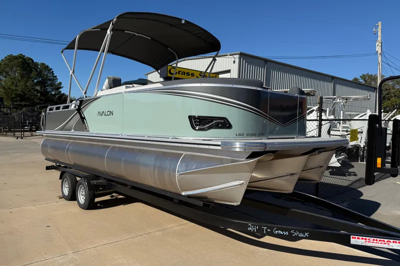 Slide: The Image of 2026 Avalon LSZ Versatile Rear Bench pontoon boat on trailer, outdoor display. - 10