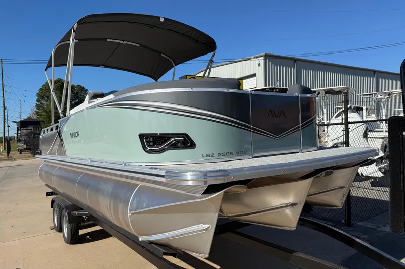 Slide: The Image of 2026 Avalon LSZ Versatile Rear Bench pontoon boat on trailer, featuring sleek design and canopy. - 2