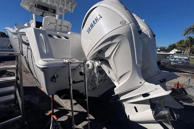 Slide: The Image of 2026 Tidewater 302 CC Adventure boat with Yamaha engines, docked under clear blue sky. - 16