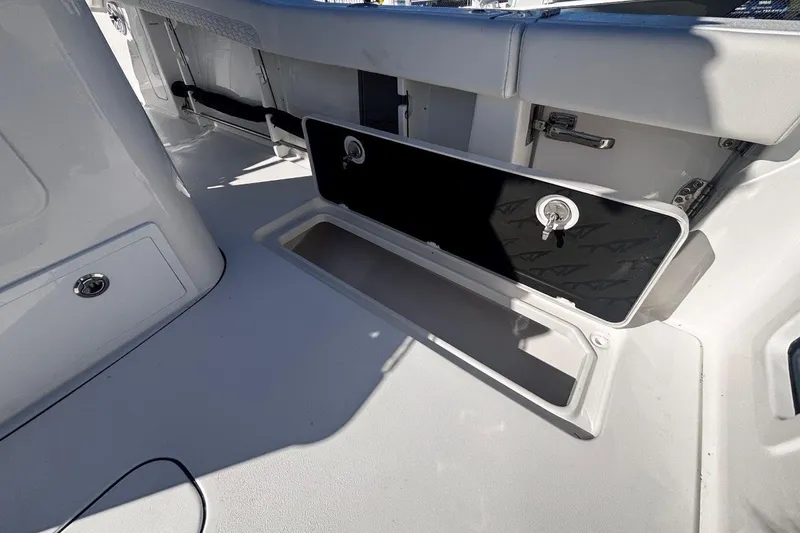 Slide: The Image of 2026 Tidewater 302 CC Adventure boat storage compartment with open hatch and key lock. - 30