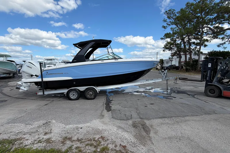 Slide: The Image of 2024 Chaparral 270 OSX boat on trailer, parked outdoors under a blue sky. - 1
