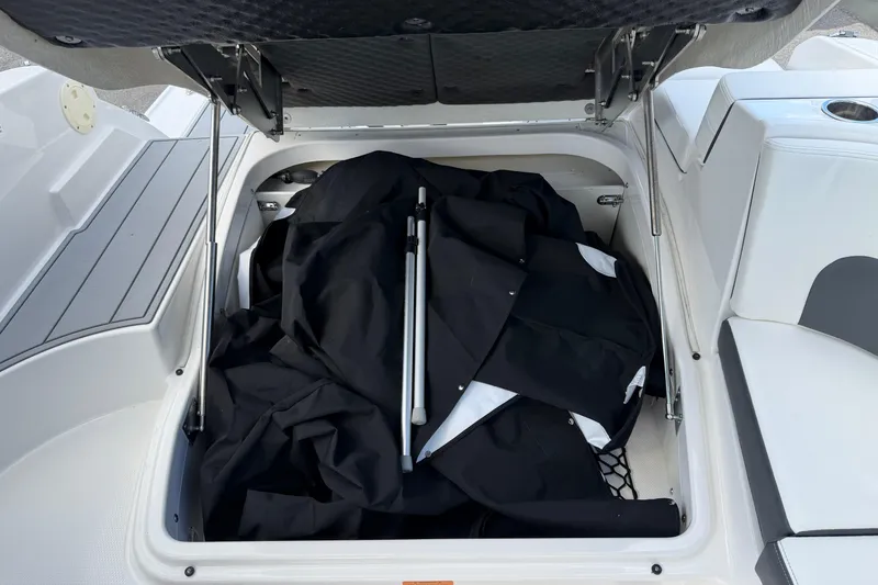 Slide: The Image of 2024 Chaparral 270 OSX boat storage compartment with black cover and poles. - 10
