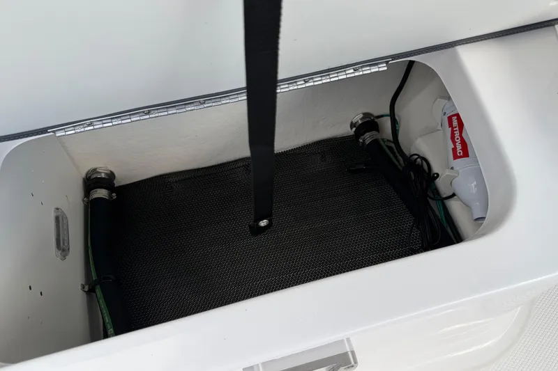 Slide: The Image of Storage compartment in 2024 Chaparral 270 OSX boat, featuring hoses and equipment. - 11