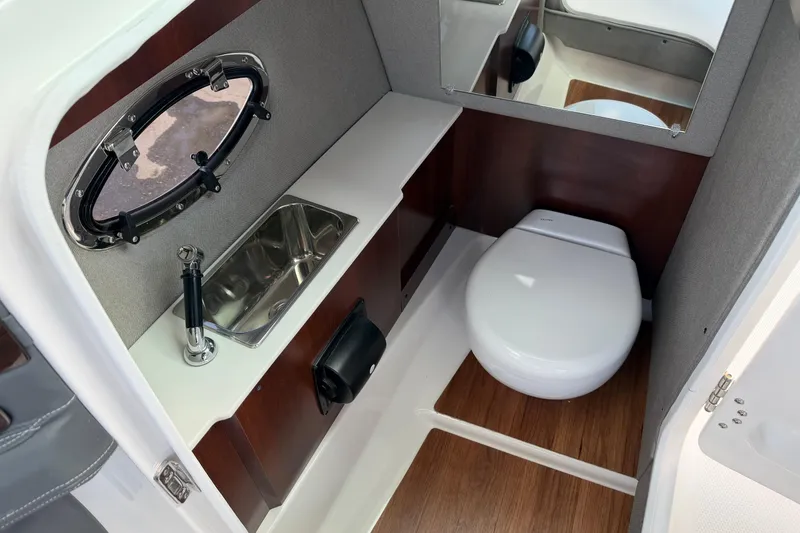 Slide: The Image of 2024 Chaparral 270 OSX boat interior with sink, toilet, and wood flooring. - 8