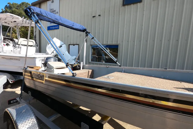 Slide: The Image of 1994 MIRRO CRAFT 15 boat with blue canopy on trailer, parked near building. - 5