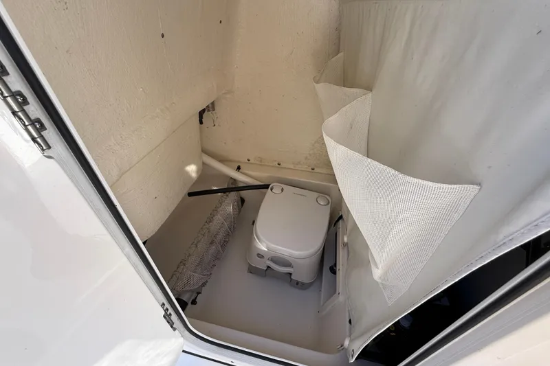Slide: The Image of 2022 Key West 239 FS boat interior with portable toilet and storage area. - 18