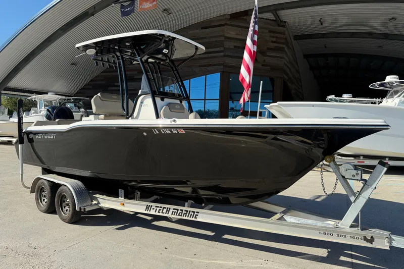 Slide: The Image of 2022 Key West 239 FS boat on trailer, displayed outdoors with American flag. - 2