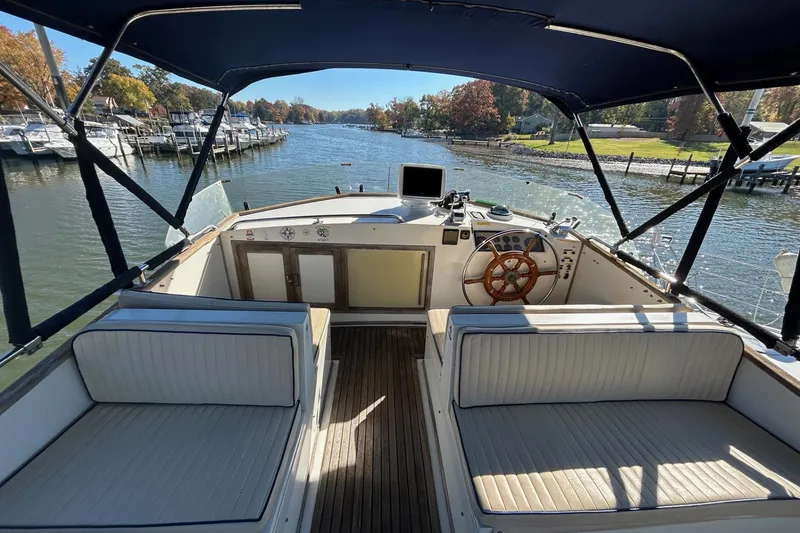 Slide: The Image of 1986 Grand Banks 42 Classic yacht helm with seating, overlooking a serene marina view. - 12