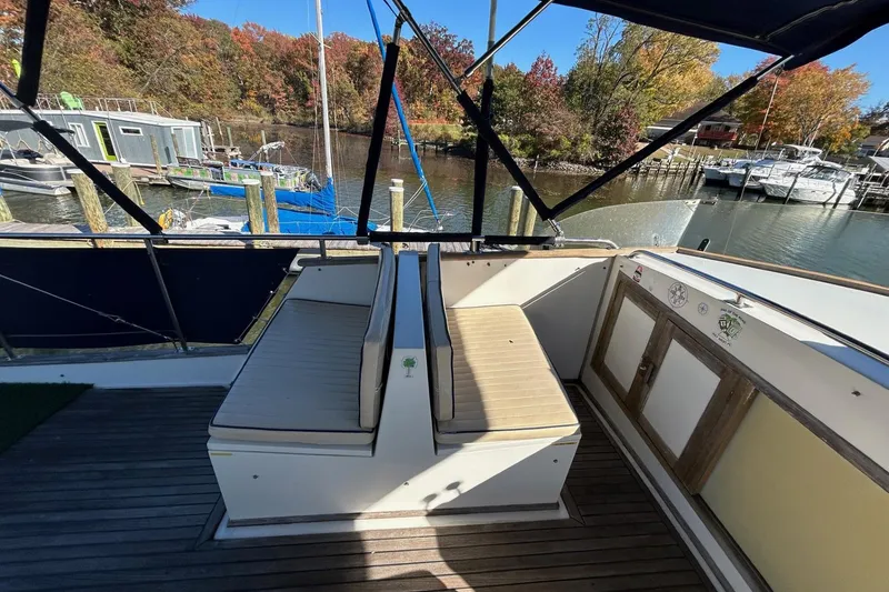 Slide: The Image of 1986 Grand Banks 42 Classic yacht deck with seating, docked by autumn trees. - 13