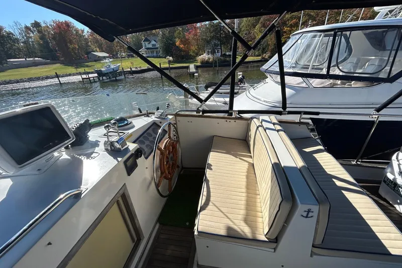 Slide: The Image of 1986 Grand Banks 42 Classic yacht cockpit with seating and steering wheel, docked by a scenic waterfront. - 14