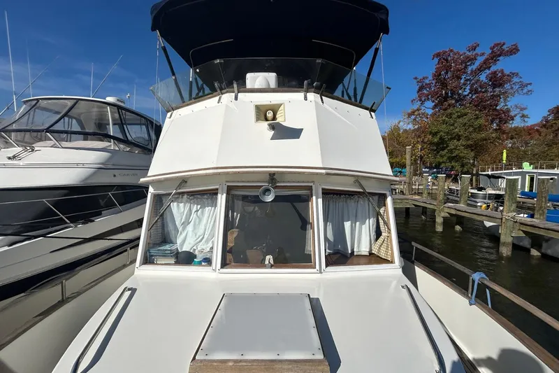 Slide: The Image of 1986 Grand Banks 42 Classic yacht docked at marina, clear sky, autumn trees in background. - 21