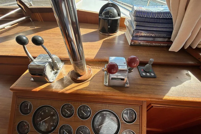 Slide: The Image of 1986 Grand Banks 42 Classic helm with controls, gauges, and navigation books. - 33
