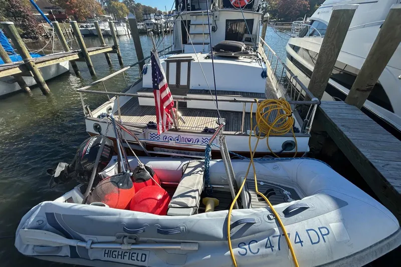 Slide: The Image of 1986 Grand Banks 42 Classic yacht docked with inflatable boat and American flag. - 4