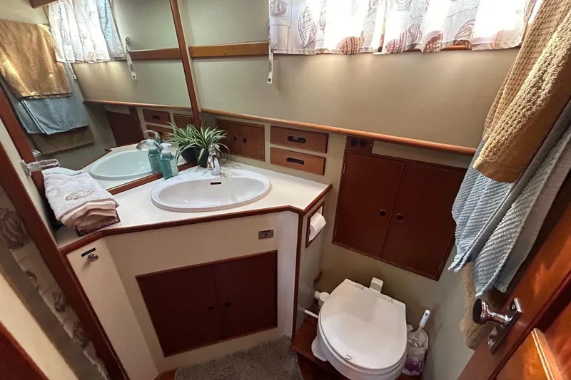 Slide: The Image of Elegant 1986 Grand Banks 42 Classic yacht bathroom with sink, toilet, and wooden cabinetry. - 42