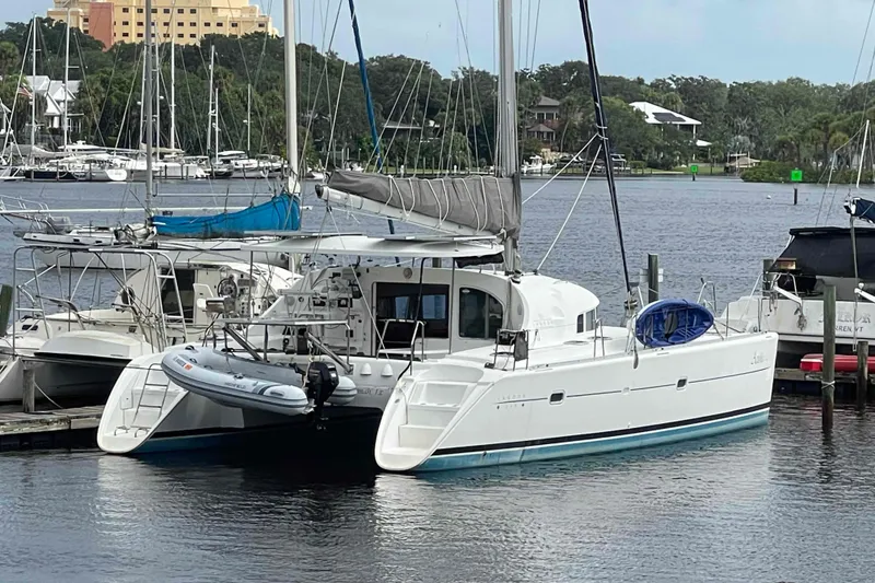 The Image of 2003 Lagoon 410-S2 catamaran docked at marina with inflatable boat. - 0