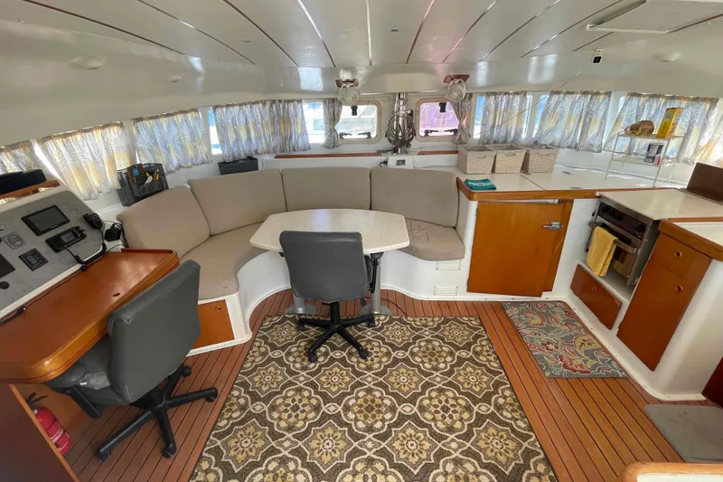 Slide: The Image of Interior of 2003 Lagoon 410-S2 catamaran with cozy seating, navigation station, and kitchen area. - 2