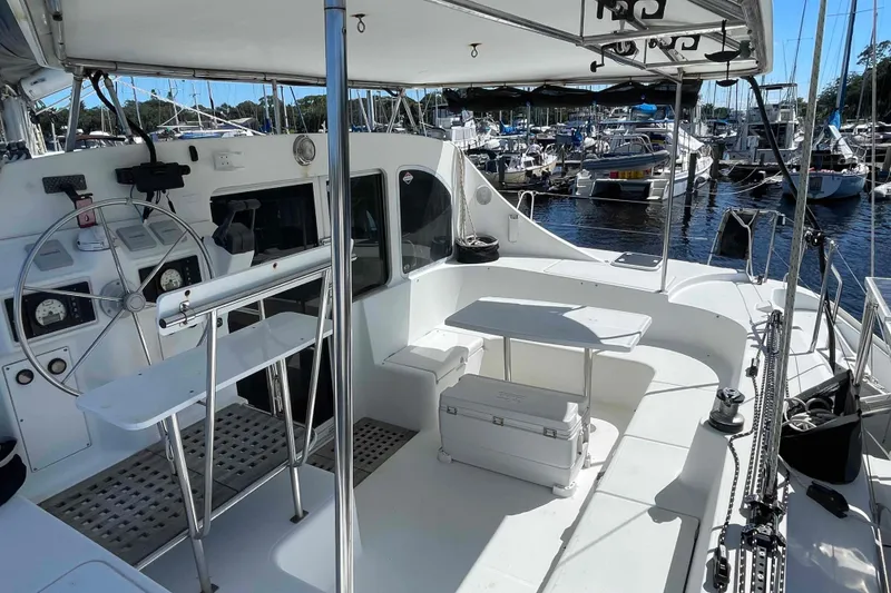 Slide: The Image of 2003 Lagoon 410-S2 catamaran cockpit with steering wheel, seating, and marina view. - 15