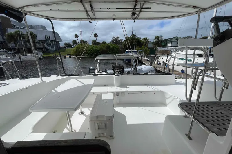 Slide: The Image of 2003 Lagoon 410-S2 catamaran cockpit with seating, table, and marina view. - 18