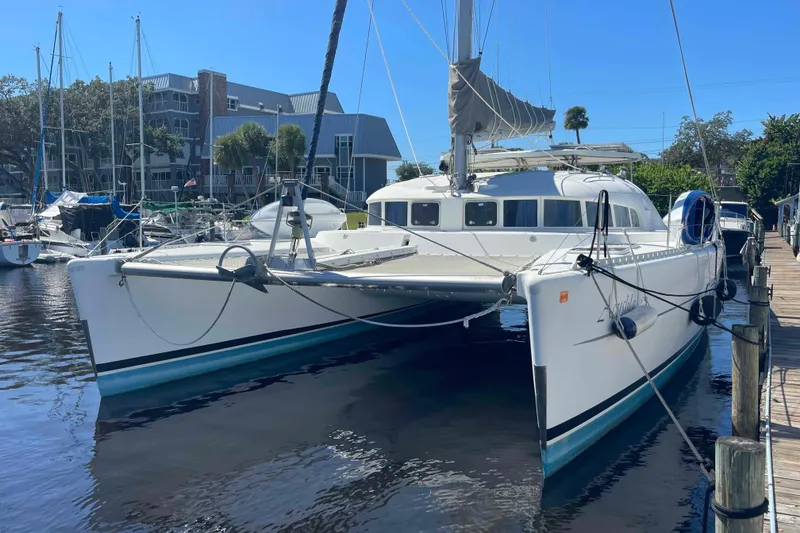 Slide: The Image of 2003 Lagoon 410-S2 catamaran docked at marina under clear blue sky. - 22