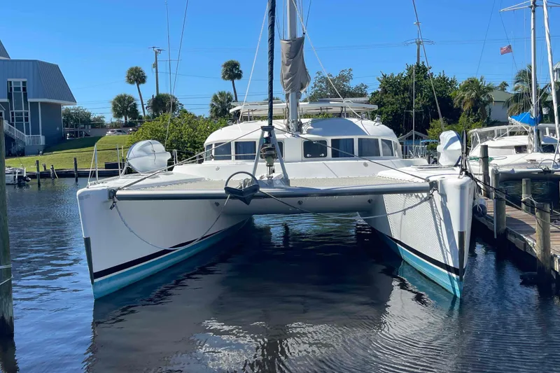 Slide: The Image of 2003 Lagoon 410-S2 catamaran docked in a sunny marina setting. - 23