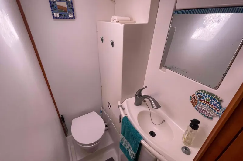 Slide: The Image of Compact bathroom in a 2003 Lagoon 410-S2 yacht with sink, toilet, and mirror. - 4