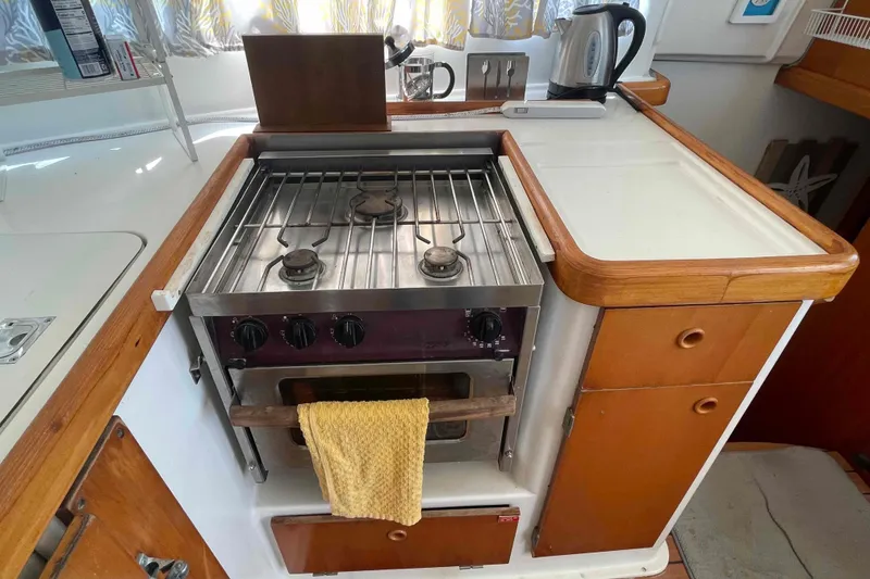 Slide: The Image of Interior of 2003 Lagoon 410-S2 yacht kitchen with stove, storage, and colorful curtains. - 40