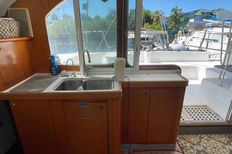 Slide: The Image of Interior view of 2003 Lagoon 410-S2 yacht kitchen with sink and outdoor access. - 7