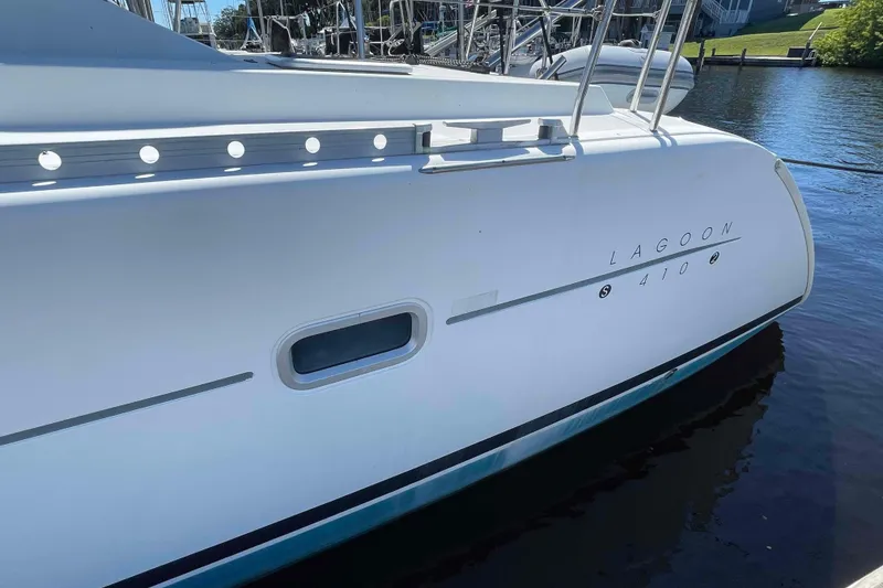 Slide: The Image of 2003 Lagoon 410-S2 catamaran cockpit with seating, table, and marina view. - 75
