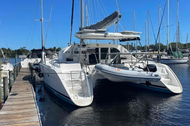 Slide: The Image of 2003 Lagoon 410-S2 catamaran with solar panels docked at a marina. - 76