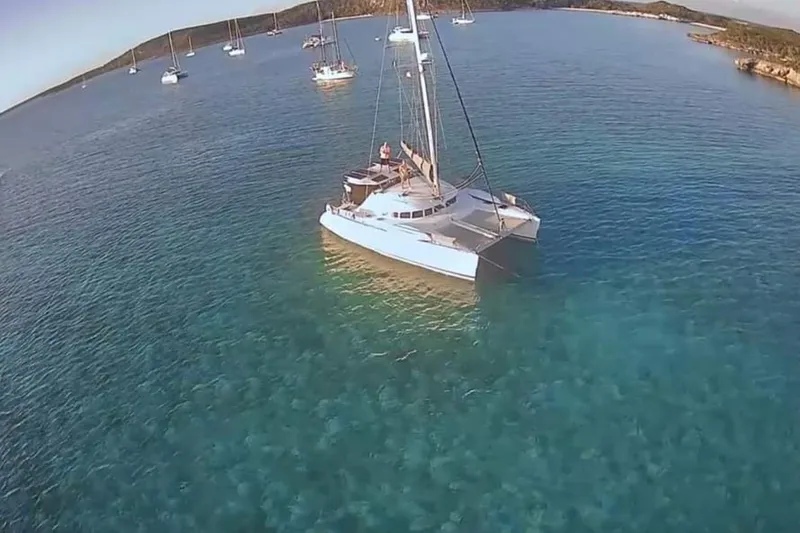 Slide: The Image of 2003 Lagoon 410-S2 catamaran on calm water at sunset, featuring sleek design and spacious deck. - 86