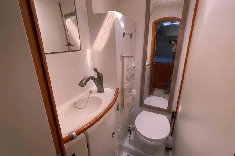 Slide: The Image of Compact bathroom in a 2003 Lagoon 410-S2 yacht, featuring a sink, mirror, and toilet. - 9