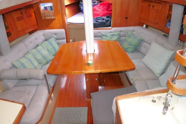Slide: The Image of 1989 C&C 37/40+ yacht interior with wooden table, cushioned seating, and cozy cabin layout. - 8