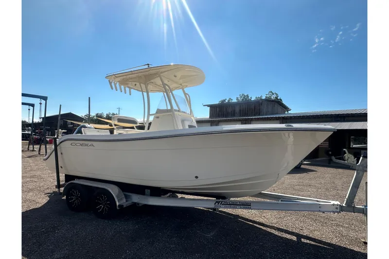 Slide: The Image of 2023 Cobia 220 Center Console boat on trailer under sunny sky. - 16