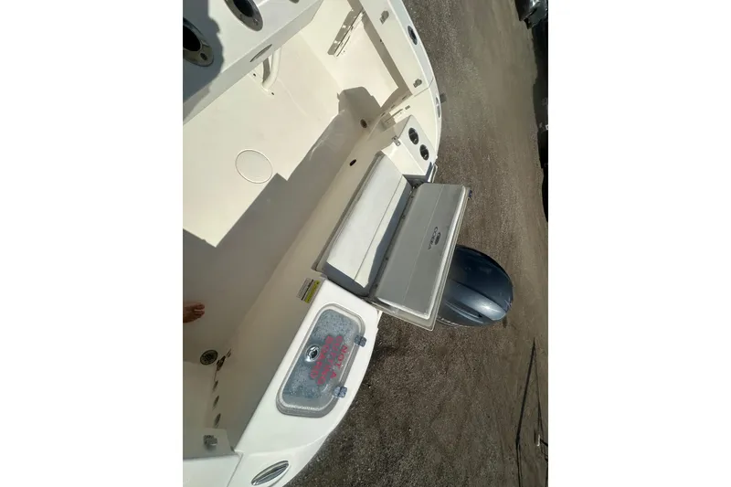 Slide: The Image of 2023 Cobia 220 Center Console boat with open storage compartments and visible outboard motor. - 27