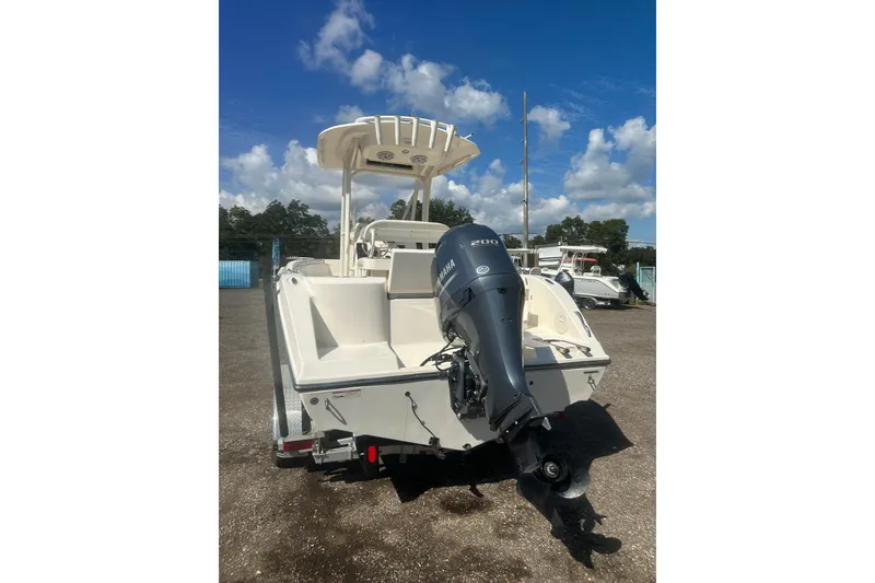 Slide: The Image of 2023 Cobia 220 Center Console boat with Yamaha engine, parked outdoors under blue sky. - 32