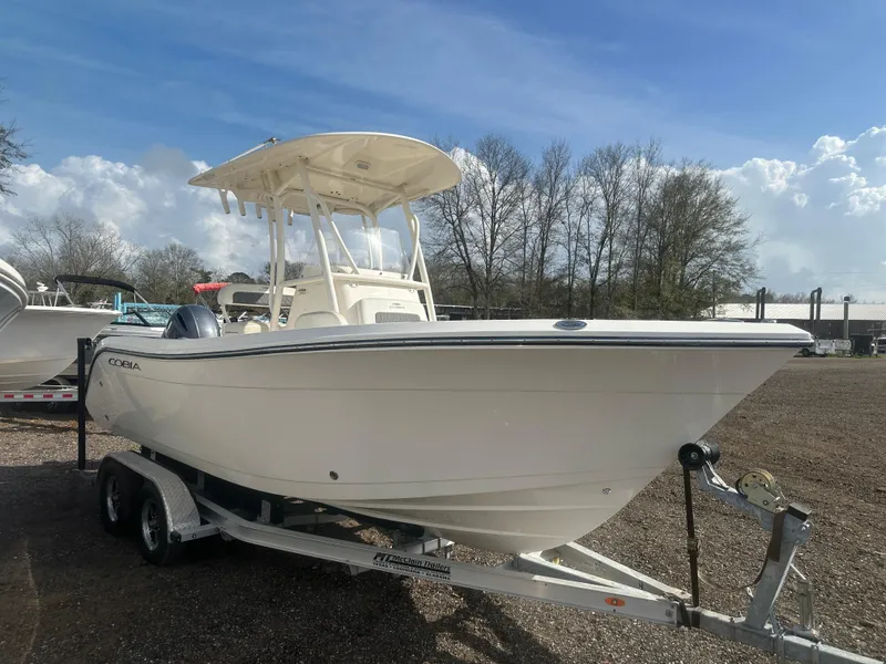 Slide: The Image of 2023 Cobia 220 CC boat on trailer, parked outdoors under a clear sky. - 6