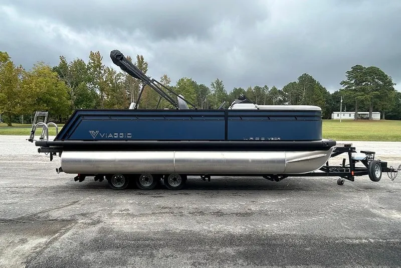 The Image of 2025 Viaggio Lago V-R pontoon boat on trailer, parked outdoors under cloudy sky. - 1