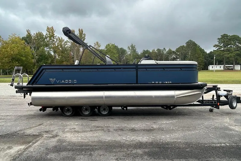 Slide: The Image of 2025 Viaggio Lago V-R pontoon boat on trailer, parked outdoors. - 4