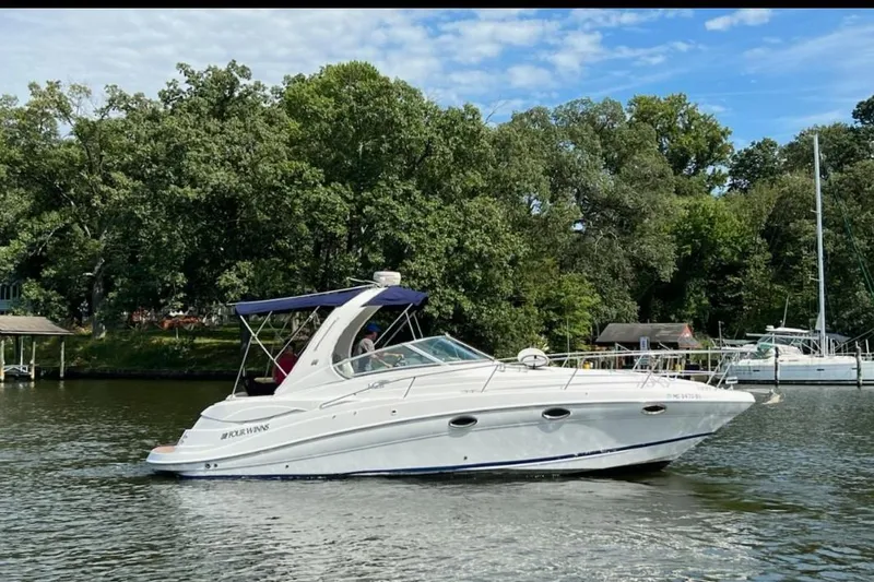 The Image of 2006 Four Winns 318 Vista boat cruising on a serene lake with lush greenery. - 0